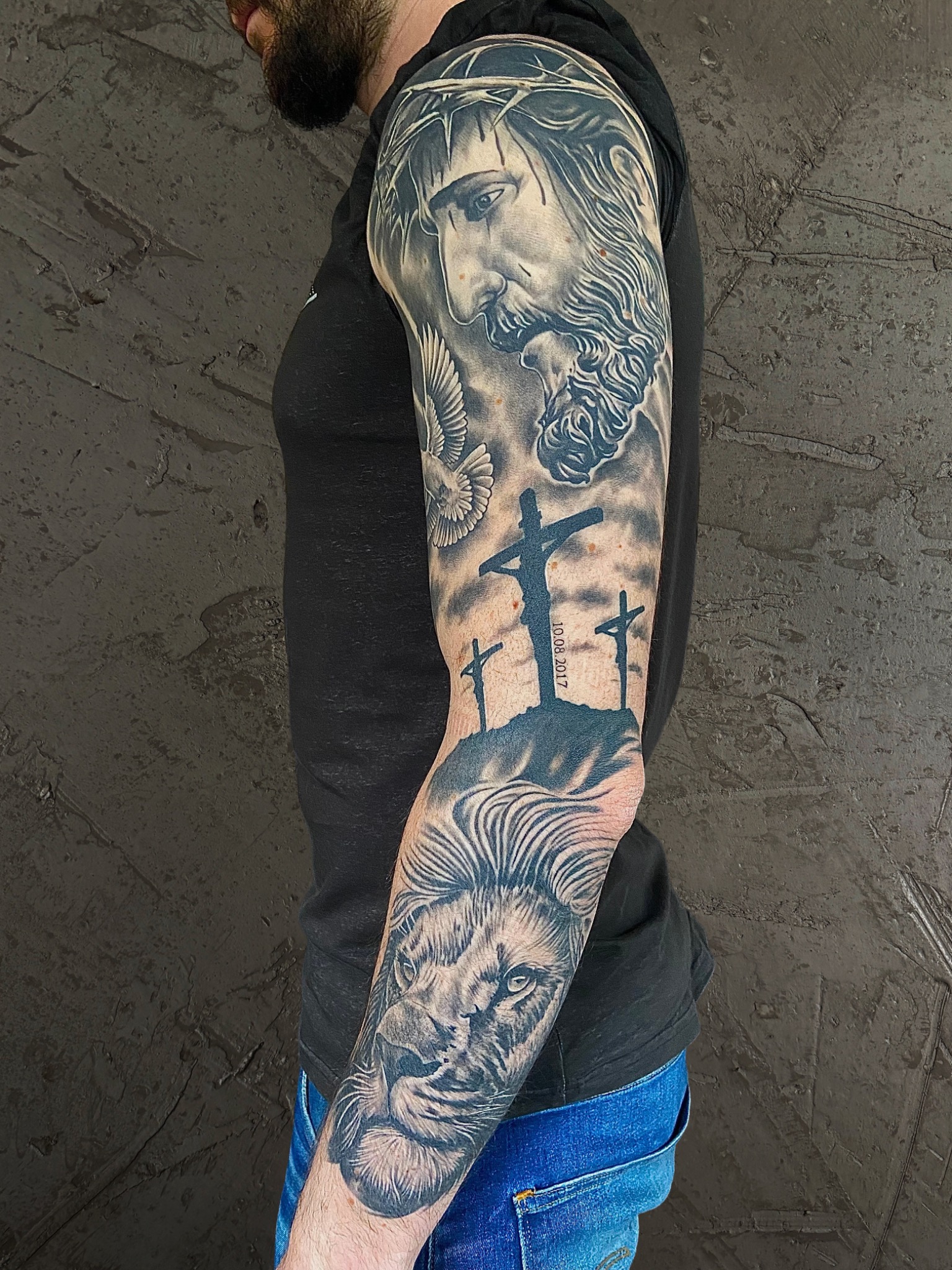 Black-and-Grey-Armtattoo mit Jesus, Kreuzen, Taube und Löwenporträt