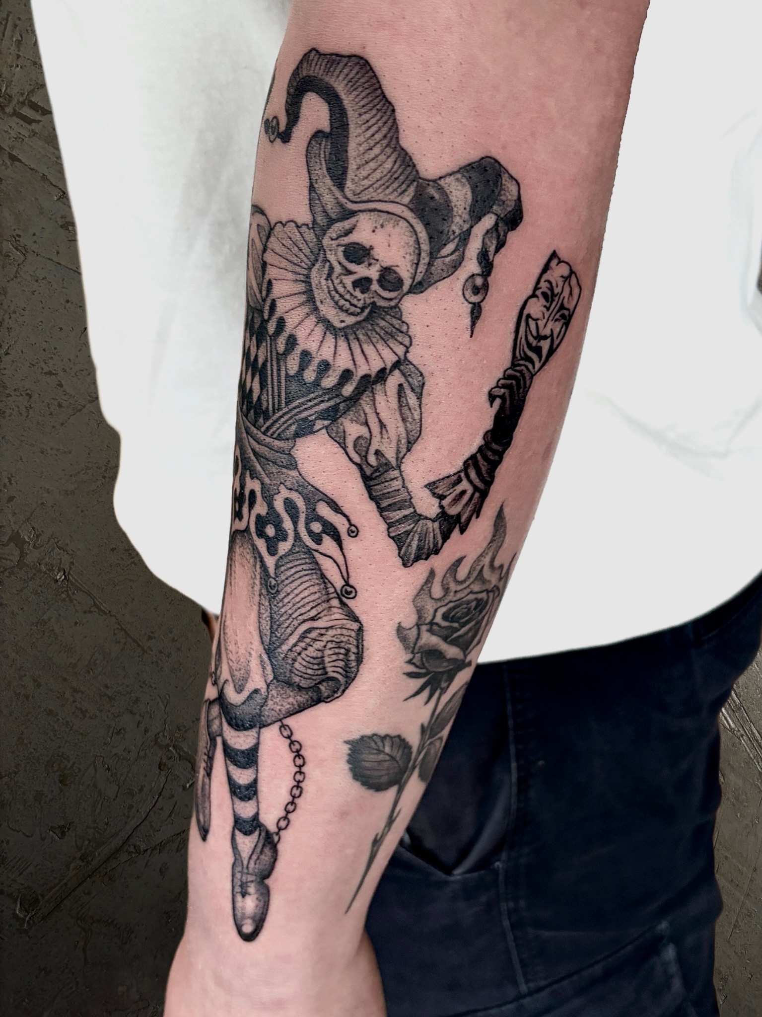 Skelettierter Hofnarr mit Maske und fein schraffierter Kleidung als Tattoo auf dem Unterarm