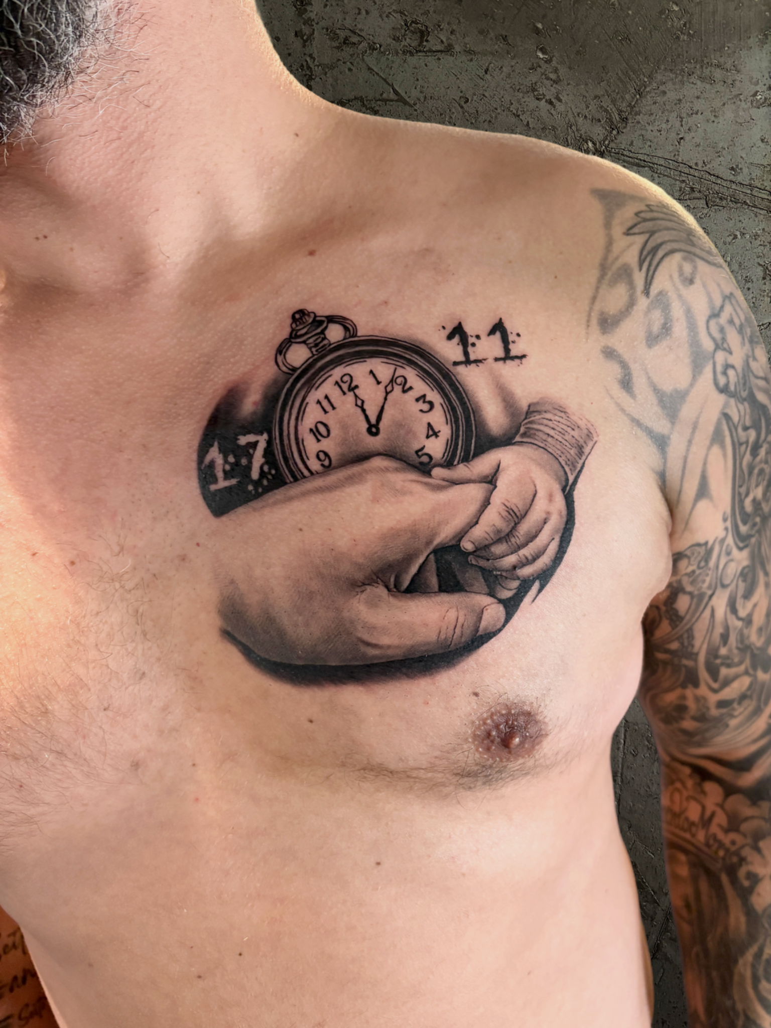 Große und kleine Hand vor einer Taschenuhr als Brusttattoo